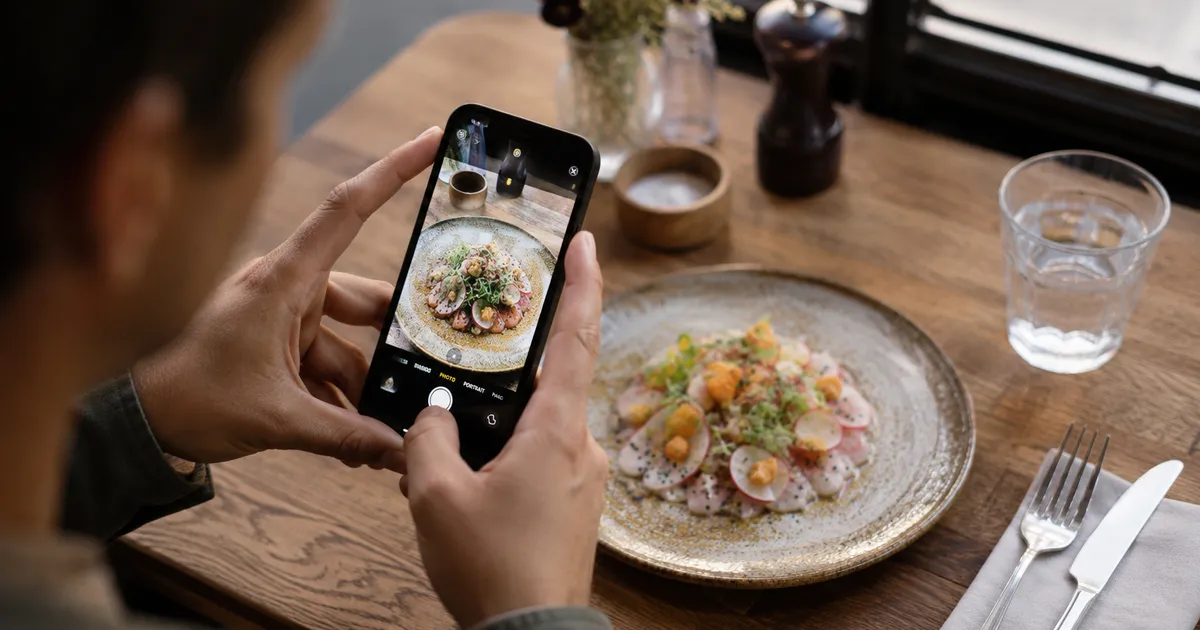 Photographing a plated dish with a smartphone in soft natural light at a restaurant table